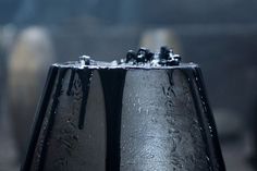 two black vases sitting next to each other on top of a wooden table covered in water