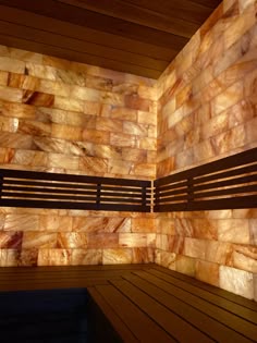 a wooden bench sitting in front of a wall covered with stone tiles and wood slats