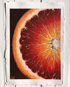an orange cut in half sitting on top of a piece of white paper next to a wooden wall