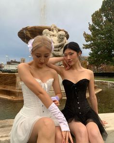 two women sitting next to each other near a fountain