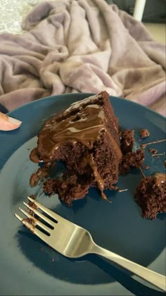 a piece of chocolate cake on a blue plate with a fork and napkin next to it