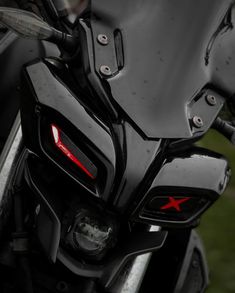 the front end of a black motorcycle with red lights on it's headlight