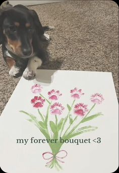 a black and brown dog laying on the floor next to a sign with flowers painted on it