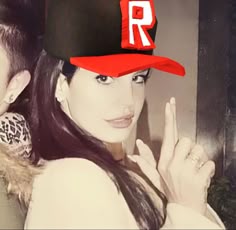 a woman wearing a red baseball cap with the letter r on it and two other people behind her