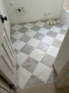 a bathroom with white and gray tile flooring next to a toilet in the corner