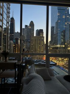 a living room filled with furniture and large windows overlooking the city at night, as seen from a high rise building
