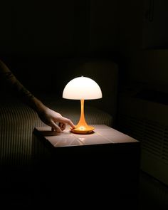 a person reaching for a lamp on a table in the dark with their hand touching it