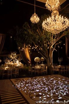 a wedding reception setup with chandeliers and flowers on the dance floor at night