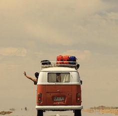 a man is standing on the roof of an old vw van in the desert