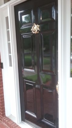 the front door is painted black and has gold hardware on it's side panel