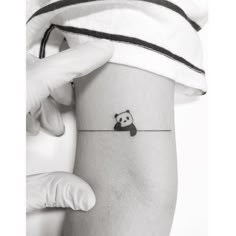 a person with a panda bear tattoo on their arm and wrist, holding onto a string