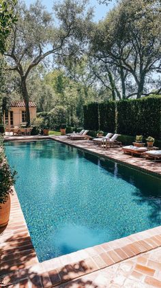 an outdoor swimming pool surrounded by trees and lawn furniture