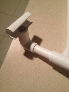 a white toilet paper dispenser sitting on top of a tiled floor next to a roll of toilet paper