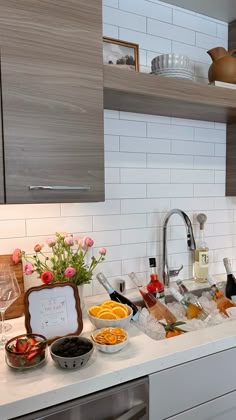 the kitchen counter is full of food and wine, with flowers in vases on it