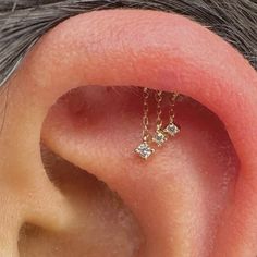a close up of a person's ear with two small diamond earrings on it