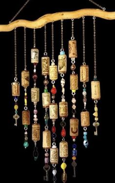 a wind chime hanging from a tree branch with beads and charms on it's sides