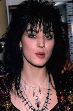 a close up of a person with black hair and necklaces on their neck,