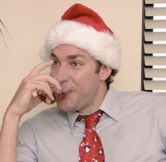 a man wearing a santa hat drinking from a wine glass