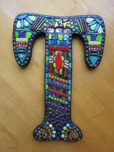 the letter t is made out of colorful glass beads and mosaics on wood flooring