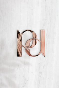 the letter h is made up of metal and copper letters on a white marble wall