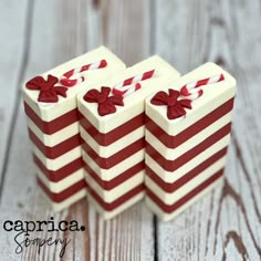 three red and white striped boxes with bows on them sitting on a wooden table next to each other