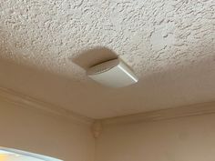 a ceiling light that is on above a window in a room with white walls and ceilings