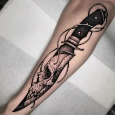 a man's arm with a knife and skull tattoo on it
