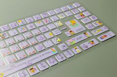 a computer keyboard covered in stickers on top of a green surface with white writing