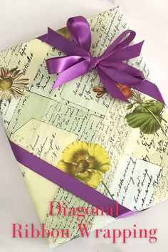 an origami box with purple ribbon and flowers on it