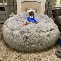 a young boy sitting in a large grey bean bag chair on top of a rug