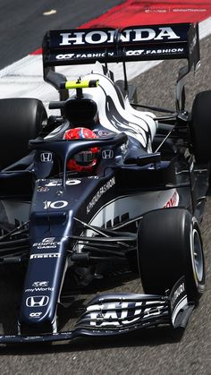 a black and white race car driving on a track with the word honda written on it