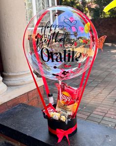 a clear balloon with some candy in it on a black table next to a building