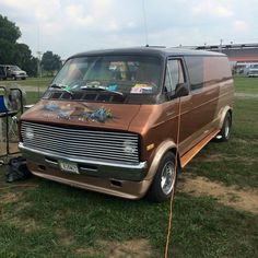 an old van is parked on the grass with other vehicles in the backgroud