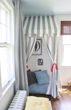 a canopy bed in the corner of a room with striped curtains on it's sides