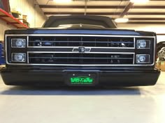 the front end of a black truck in a garage