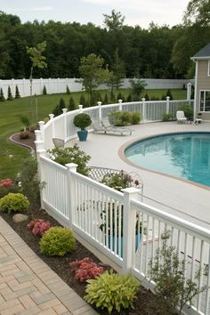 a pool with a white fence surrounding it and landscaping around the pool area is shown