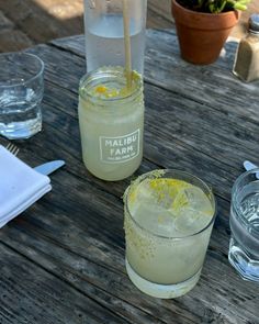 two glasses filled with lemonade sitting on top of a wooden table