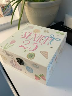 a white box sitting on top of a table next to a potted plant