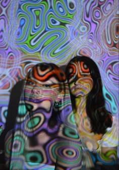 two women standing next to each other in front of a colorful background