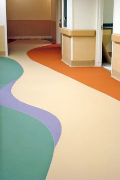 an empty room with colorful flooring and cabinets in the back drop off area is shown