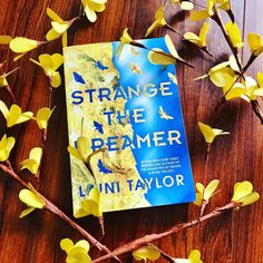a book sitting on top of a wooden table next to yellow flowers and branches in front of it