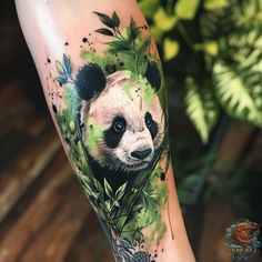 a panda bear with leaves and flowers on his arm is shown in this artistic tattoo design