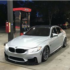a silver car parked in front of a gas pump
