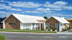 two wooden houses sitting next to each other on the side of a road with blue skies and white clouds in the background