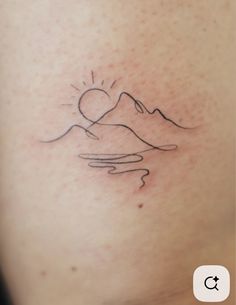 a small tattoo on the back of a woman's right thigh, with mountains in the background
