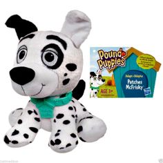 a stuffed animal with a green collar and black spots on it's face next to a box of puppy puppies