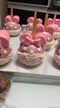 there are many pink cupcakes with bows on them that are ready to be eaten