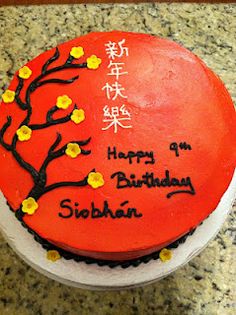 a red birthday cake with yellow flowers and writing on the top is sitting on a table