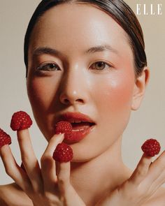 a woman holding raspberries in front of her face with the word eleva written on it