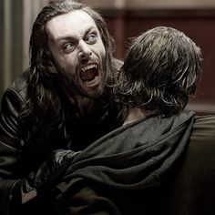 a man with long hair is being hugged by another man in a black robe and cape